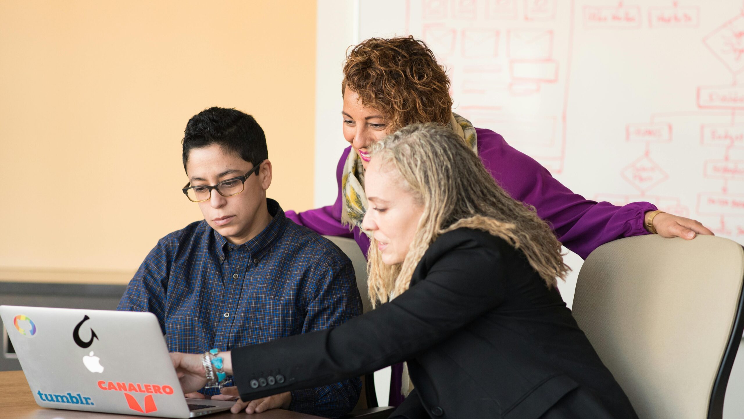 three people working and looking on a laptop screen illustrating elicitation activities in engineering