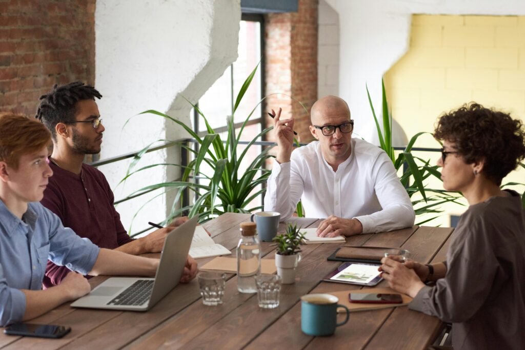 a person talking to other all sitting at a table illustrating presentation requirements engineering