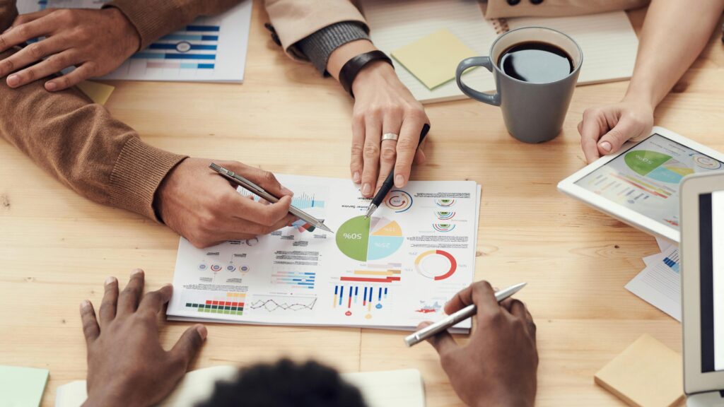 Hands of three people on a table with a paper with a chart doing best practices for documenting requirements in agile development