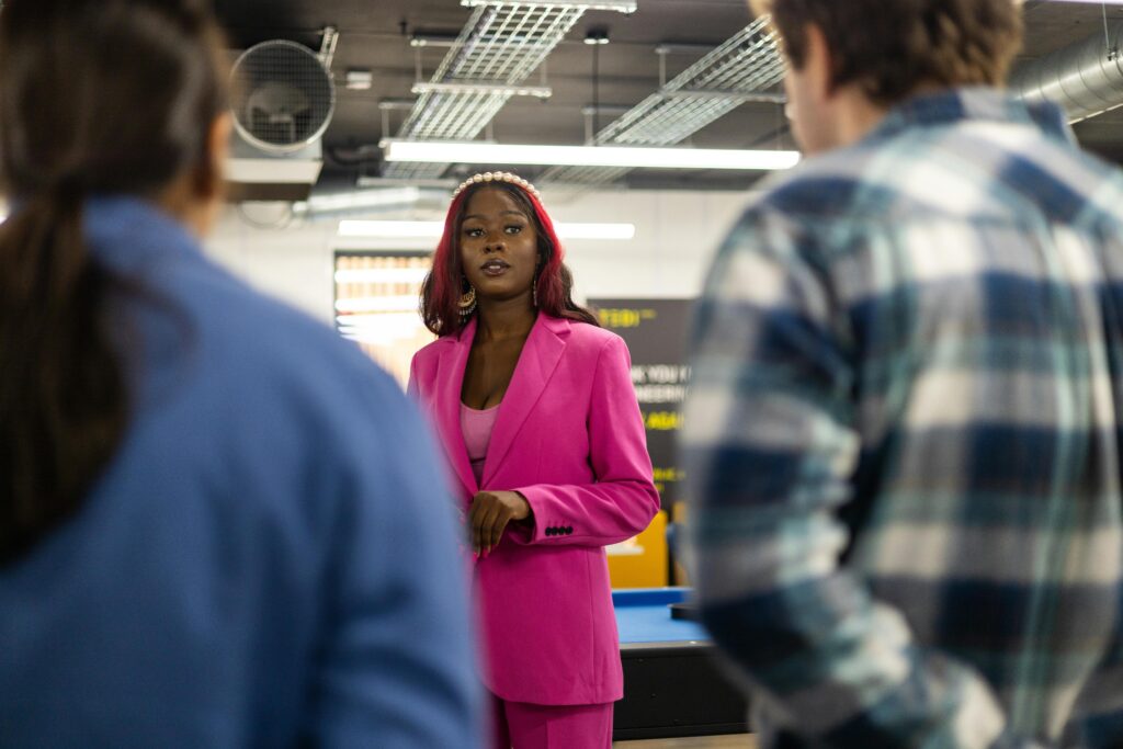 a woman in a pink business dress talking to two people representing requirements engineering with elicitation techniques