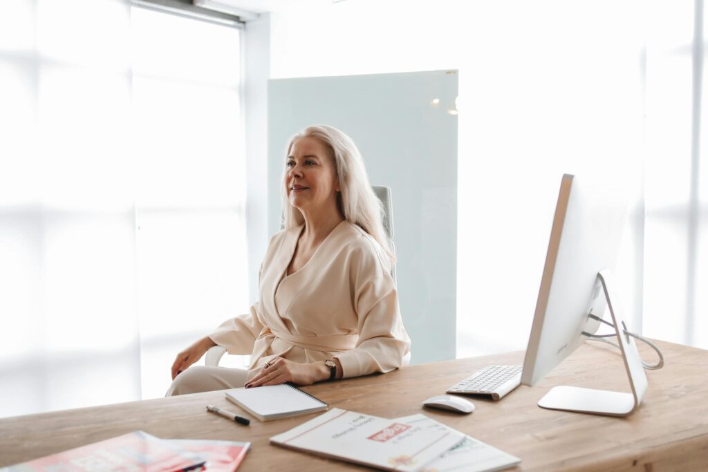 a woman sitting on a desk smiling friendly illustrating the Biopsychosocial Model in Requirements Engineering