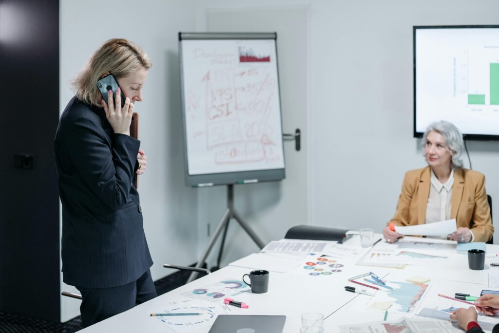 a woman on the phone evaluated by a older business woman illustrating being quick-witted in requirements engineering
